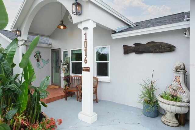 doorway to property featuring a shingled roof and stucco siding