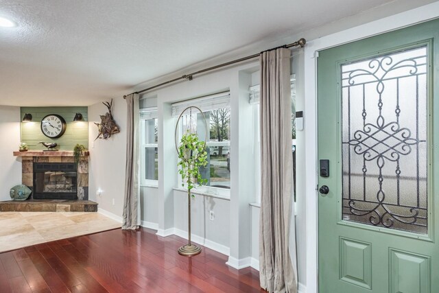 entrance foyer featuring baseboards, a textured ceiling, dark wood finished floors, and a tile fireplace