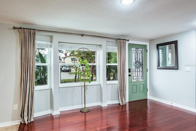 doorway to outside with a healthy amount of sunlight, a textured ceiling, baseboards, and wood finished floors