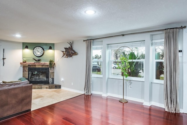 interior space featuring a fireplace, a textured ceiling, baseboards, and wood finished floors