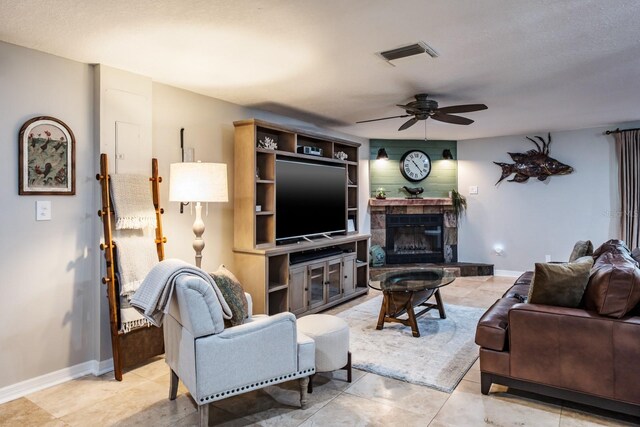 living area featuring a glass covered fireplace, visible vents, baseboards, and ceiling fan