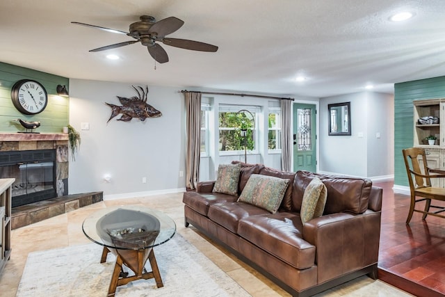 living room with baseboards, recessed lighting, a tile fireplace, a textured ceiling, and a ceiling fan