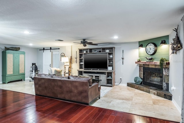 living room featuring a barn door, baseboards, wood finished floors, and a fireplace