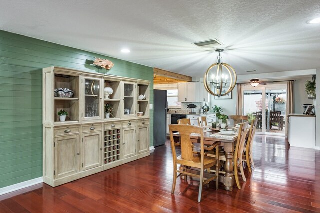 dining space featuring a textured ceiling, visible vents, dark wood-type flooring, and a notable chandelier