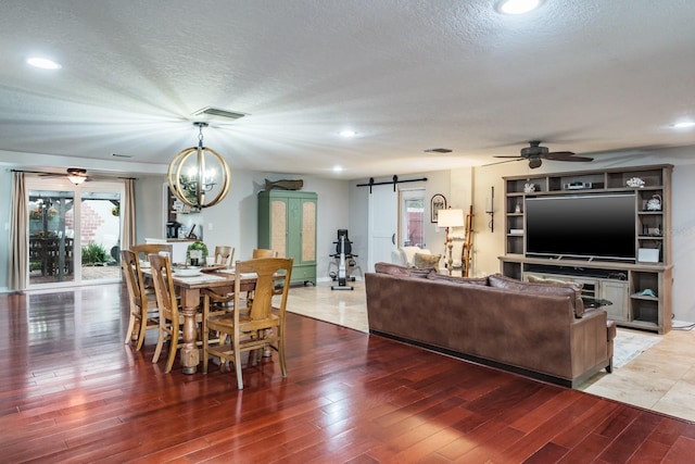 living area with a barn door, light wood-type flooring, and a textured ceiling