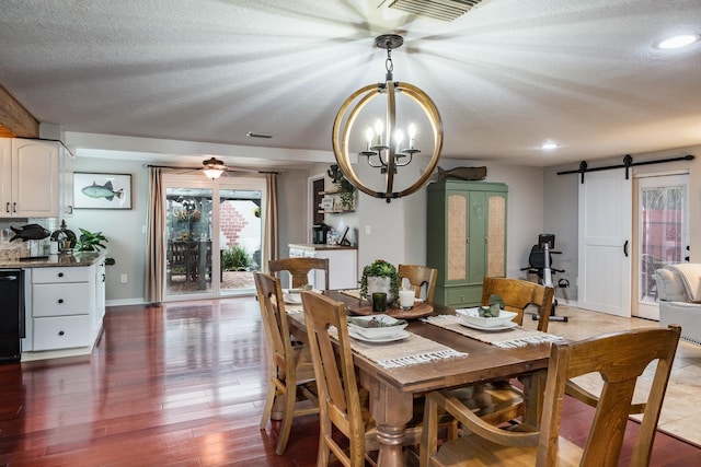 dining space featuring wood finished floors, baseboards, visible vents, a textured ceiling, and a barn door