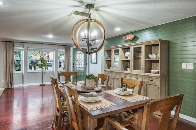 dining space featuring visible vents, a textured ceiling, dark wood-style floors, an inviting chandelier, and baseboards