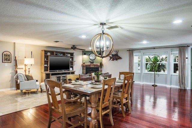 dining area featuring wood finished floors, a fireplace, visible vents, and a textured ceiling