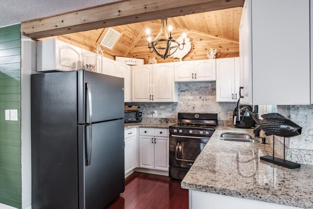 kitchen featuring black gas range, light stone counters, vaulted ceiling, and freestanding refrigerator