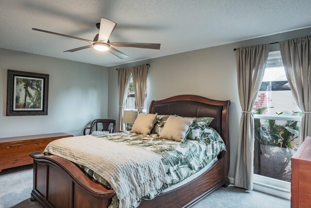 carpeted bedroom featuring multiple windows, a textured ceiling, and ceiling fan