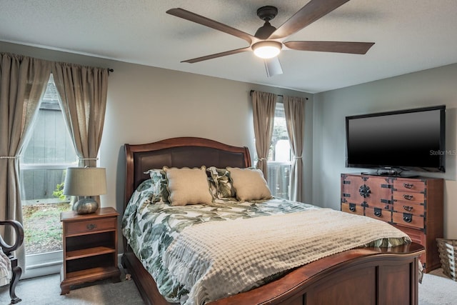 carpeted bedroom featuring ceiling fan and a textured ceiling