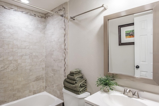 full bath with shower / bath combination, toilet, vanity, and a textured wall