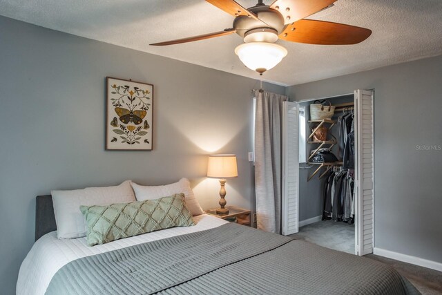 carpeted bedroom featuring a closet, baseboards, a textured ceiling, and a ceiling fan