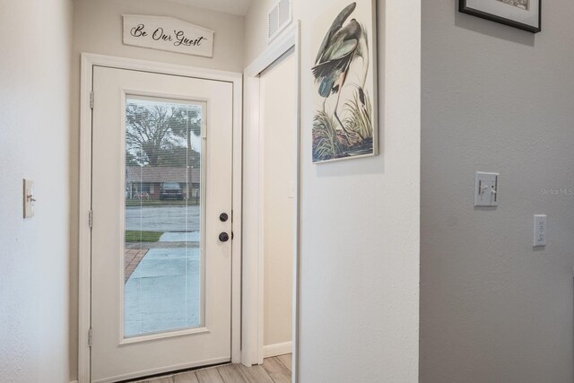 entryway with baseboards, visible vents, and light wood finished floors