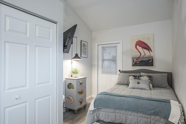 bedroom featuring vaulted ceiling, baseboards, a closet, and light wood finished floors