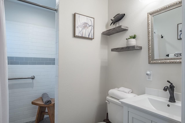 full bathroom with a tile shower, toilet, and vanity