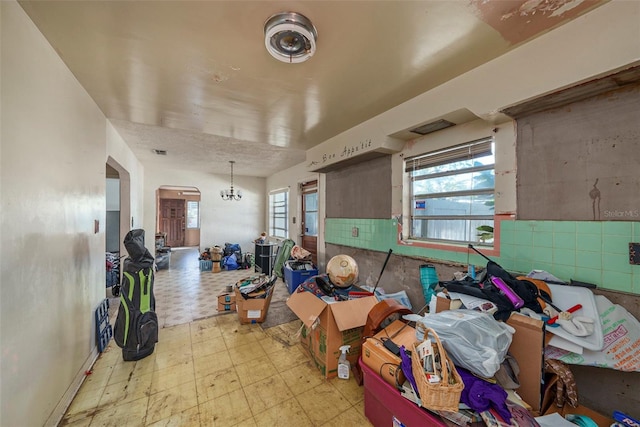 miscellaneous room featuring a notable chandelier and light floors