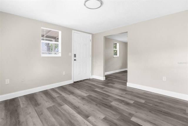 unfurnished room featuring dark wood-style floors, plenty of natural light, and baseboards