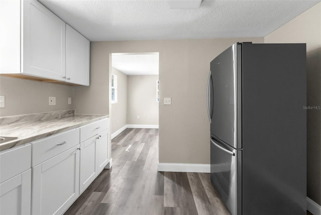 kitchen featuring a textured ceiling, white cabinets, dark wood finished floors, and freestanding refrigerator