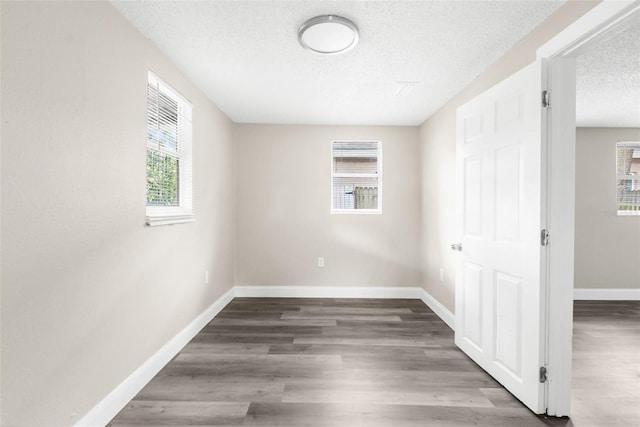 spare room with baseboards, a textured ceiling, and wood finished floors