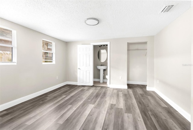 unfurnished bedroom featuring a closet, visible vents, baseboards, and wood finished floors