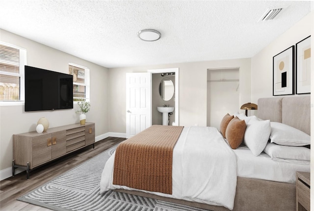 bedroom featuring visible vents, baseboards, a textured ceiling, and wood finished floors