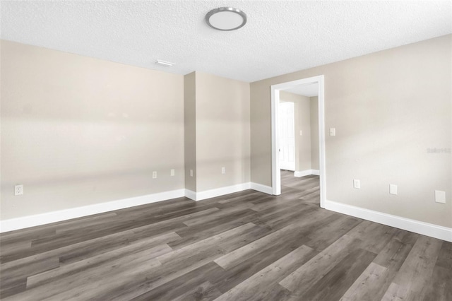 empty room with baseboards, a textured ceiling, and dark wood finished floors