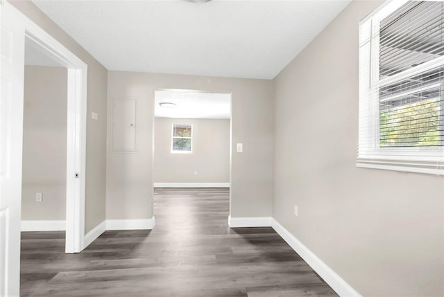 hallway with electric panel, wood finished floors, and baseboards