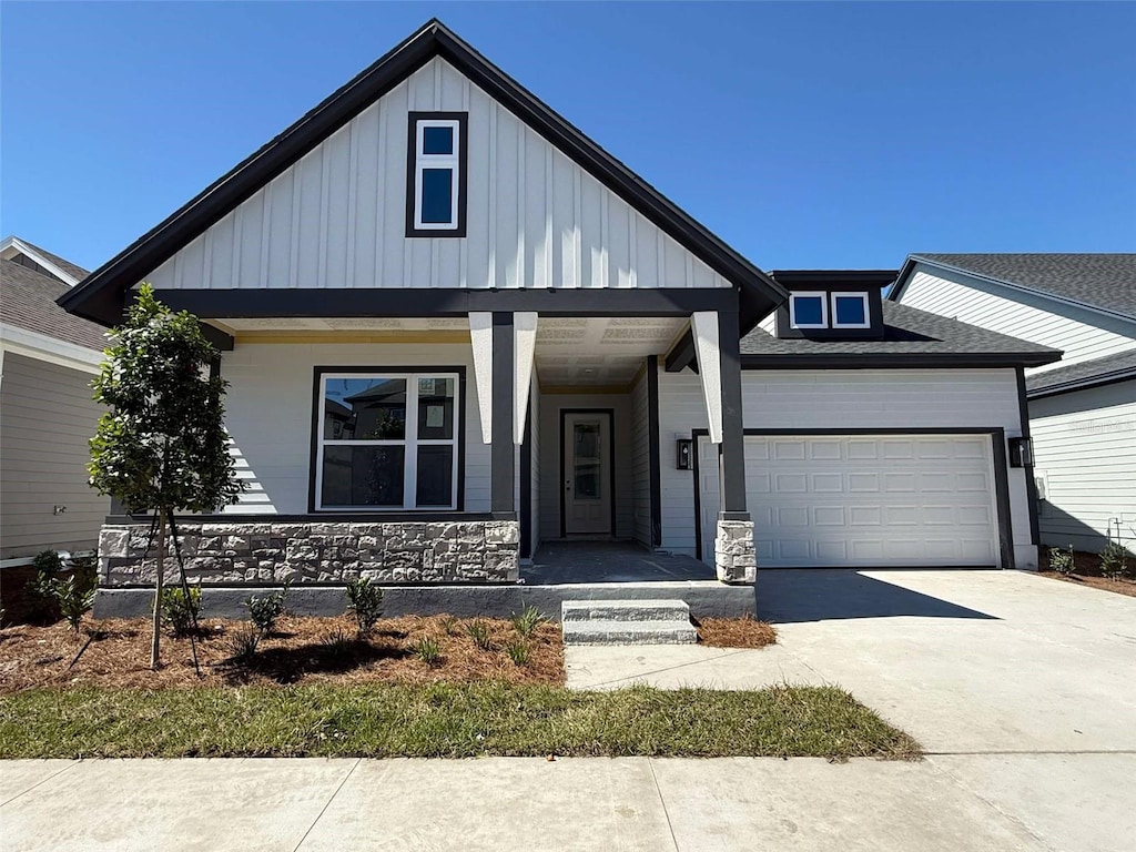 view of front of home featuring board and batten siding, covered porch, concrete driveway, and an attached garage