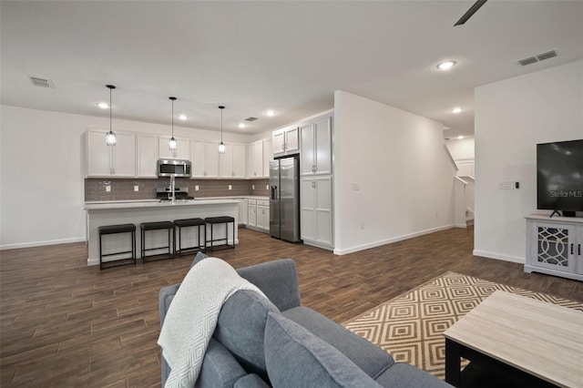 living room featuring dark wood-style floors, visible vents, and recessed lighting