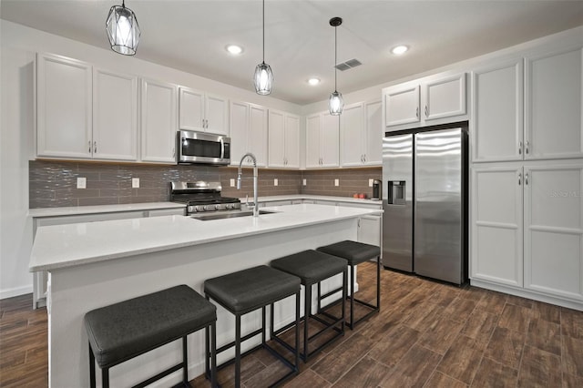 kitchen featuring decorative backsplash, visible vents, dark wood-style flooring, and stainless steel appliances