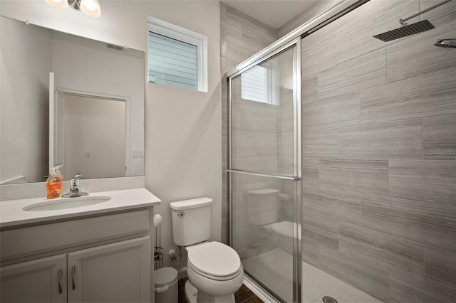 full bath featuring vanity, a shower stall, toilet, and visible vents