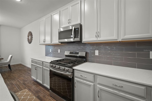 kitchen with backsplash, appliances with stainless steel finishes, light countertops, and dark wood-type flooring