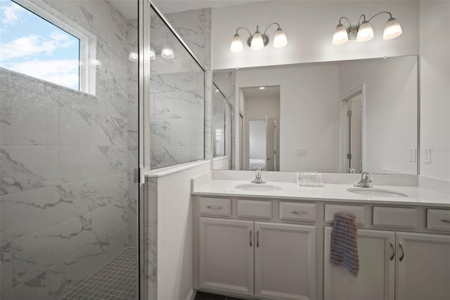 bathroom with a sink, a marble finish shower, and double vanity