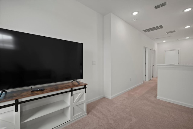 hallway with visible vents, baseboards, and light colored carpet