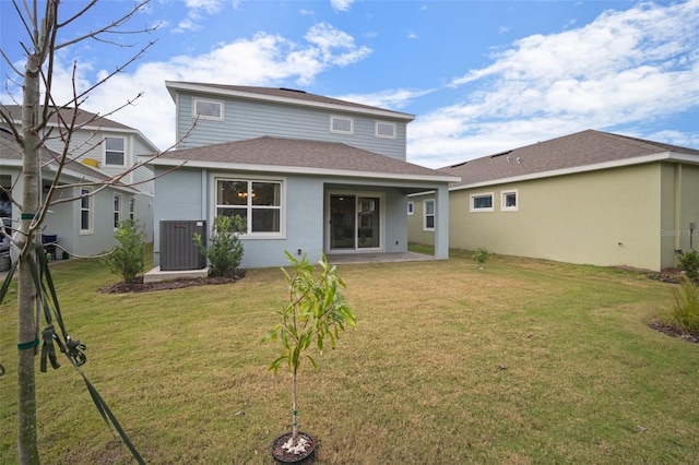 back of house with a yard, a shingled roof, stucco siding, central air condition unit, and a patio area