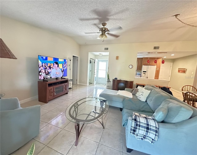 living area with visible vents, baseboards, ceiling fan, light tile patterned floors, and a textured ceiling