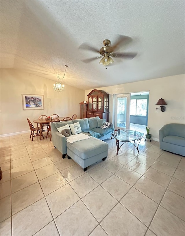 living area featuring light tile patterned floors, baseboards, a textured ceiling, and ceiling fan with notable chandelier