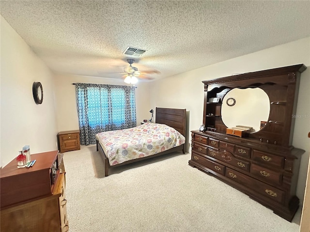 carpeted bedroom with visible vents, a textured ceiling, and a ceiling fan