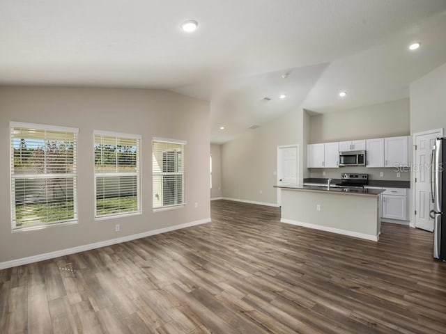 kitchen with dark wood-style flooring, white cabinets, appliances with stainless steel finishes, dark countertops, and open floor plan