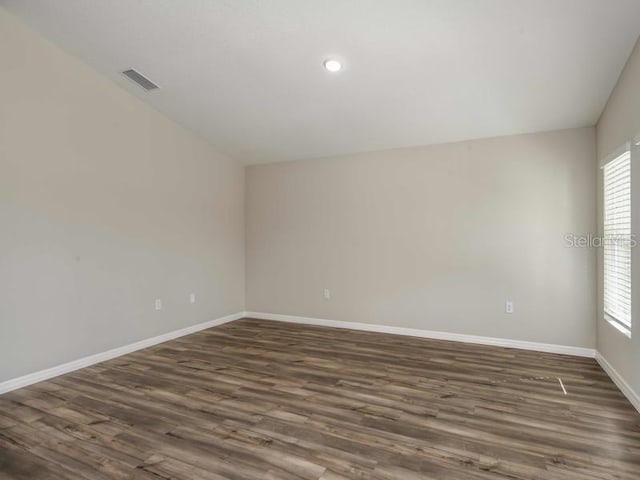 spare room featuring dark wood-style floors, visible vents, and baseboards