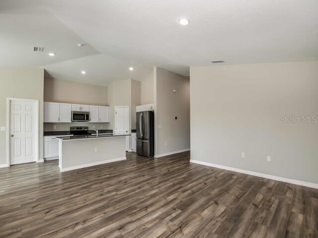 kitchen featuring visible vents, white cabinets, appliances with stainless steel finishes, dark countertops, and open floor plan