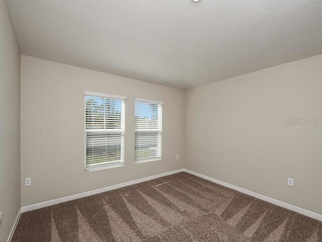 carpeted spare room with baseboards and a textured ceiling