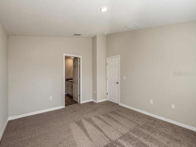 unfurnished room with dark carpet, baseboards, and lofted ceiling