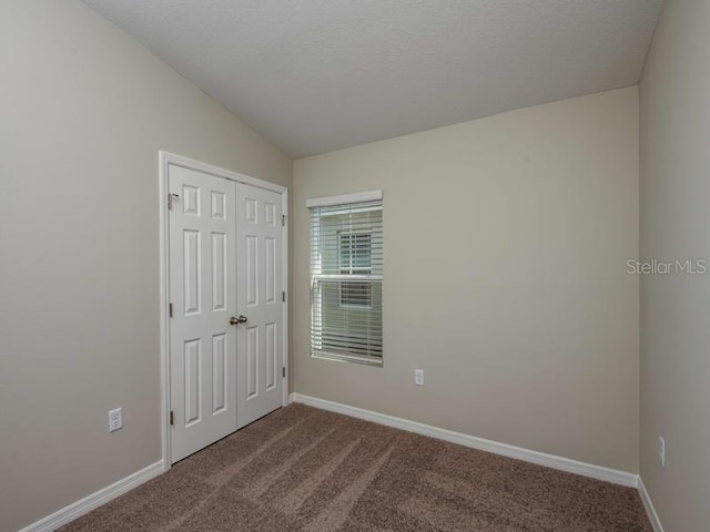 empty room featuring lofted ceiling, baseboards, and carpet floors