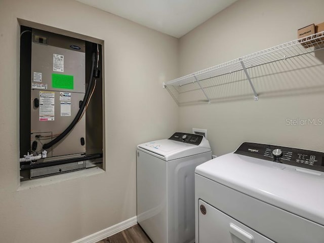 laundry area featuring heating unit, baseboards, washing machine and clothes dryer, dark wood finished floors, and laundry area