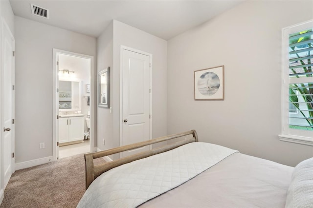 carpeted bedroom featuring visible vents, connected bathroom, and baseboards