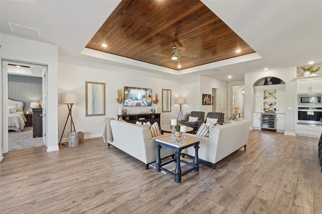 living room with a raised ceiling, wine cooler, wooden ceiling, and light wood finished floors