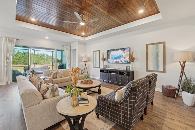 living room with a raised ceiling, wood ceiling, and baseboards