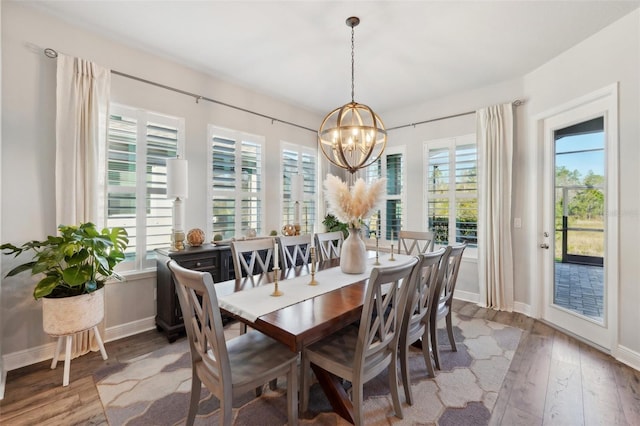 dining space featuring a chandelier, a healthy amount of sunlight, and wood finished floors